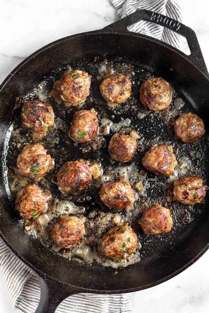 Cast iron filled with cooked lamb meatballs.