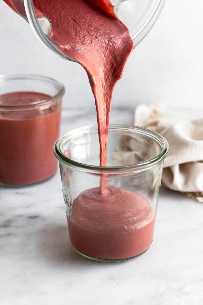 Creamy reddish pink smoothie being poured into a large glass.