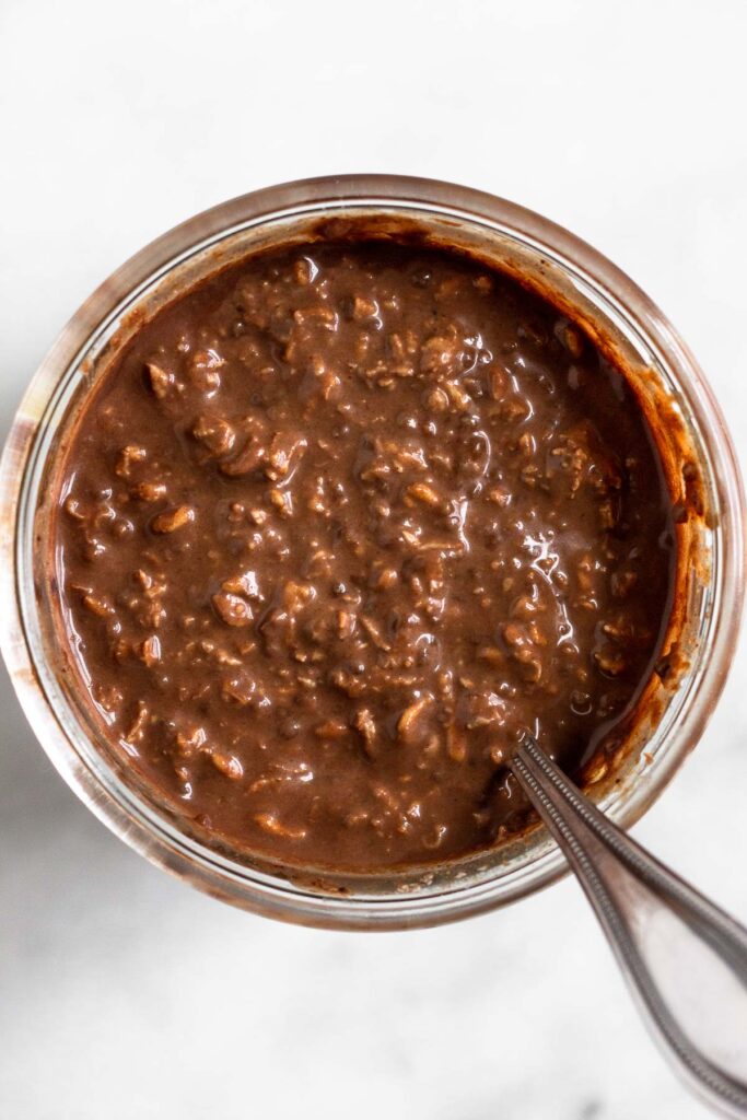 Overhead shot of chocolate overnight oats in a jar with in a spoon in the jar.