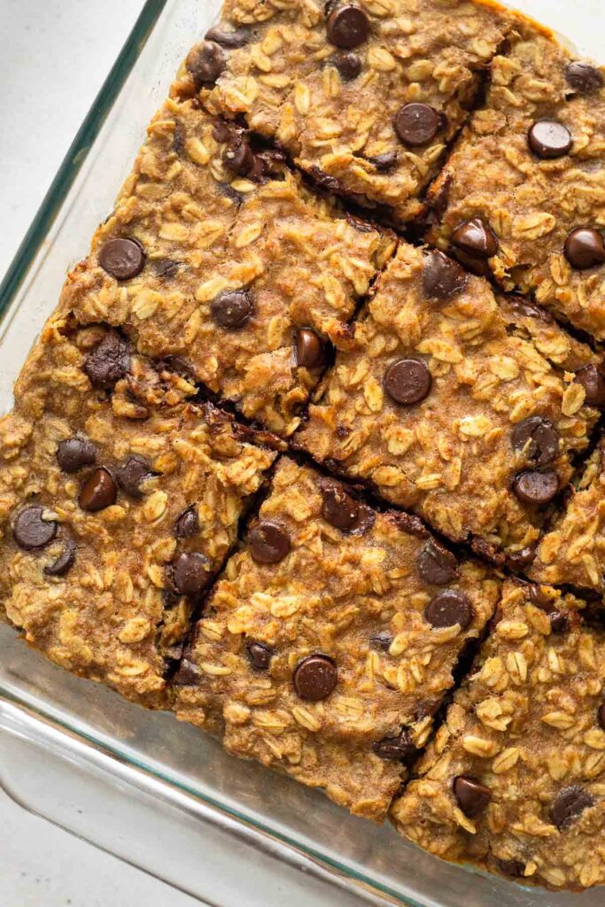 Close up of a chocolate chip oatmeal bars in a glass baking dish. They are cut into equal-size pieces.