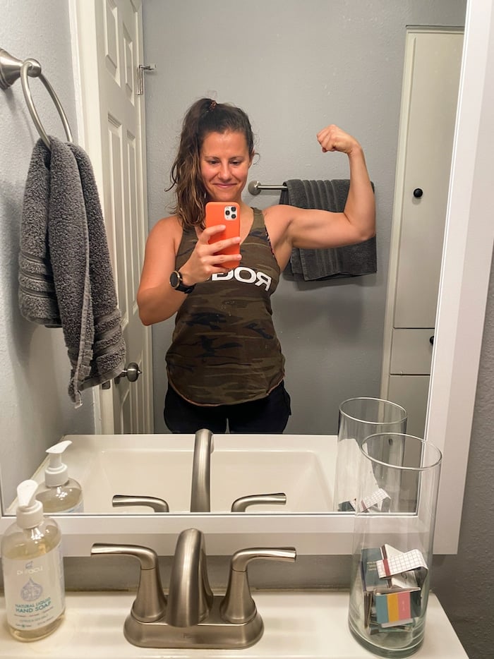 A woman flexing in the mirror taking a selfie.