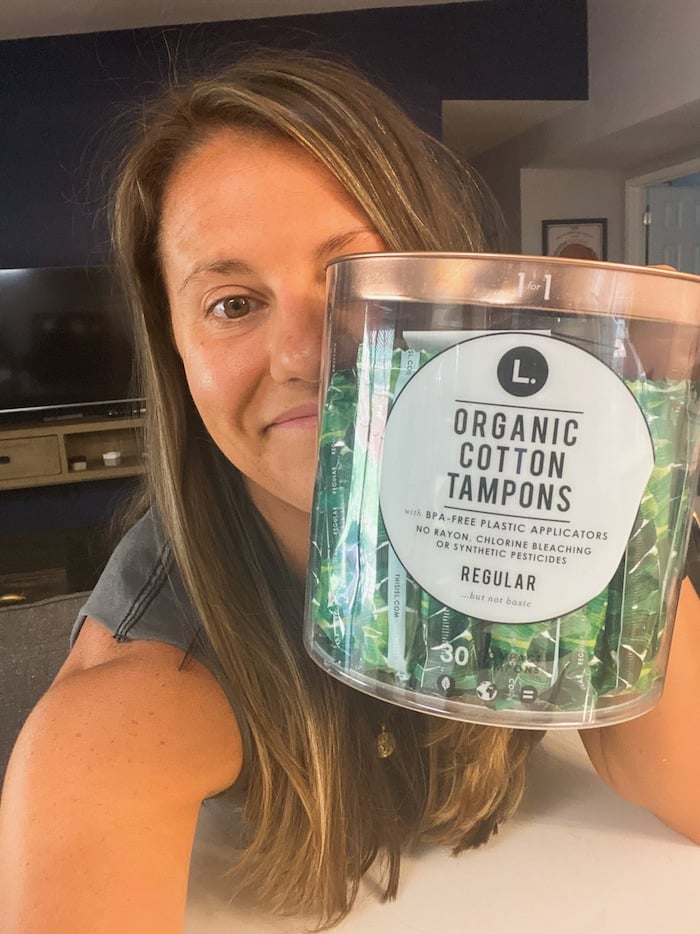 Girl taking a selfie holding a container of organic tampons.