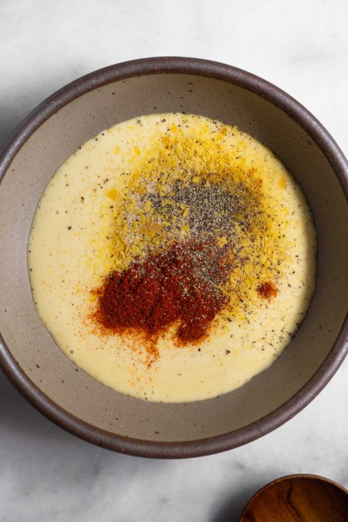 A small bowl with mayo and spices sprinkled overtop of it.