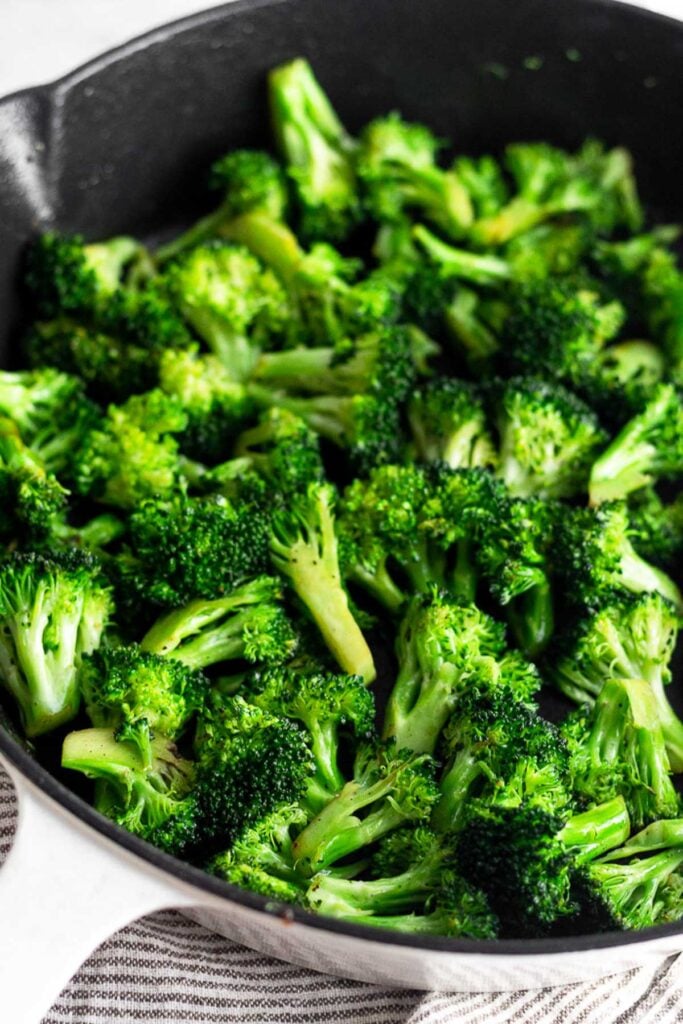 Cast iron skillet filled with sautéed broccoli.