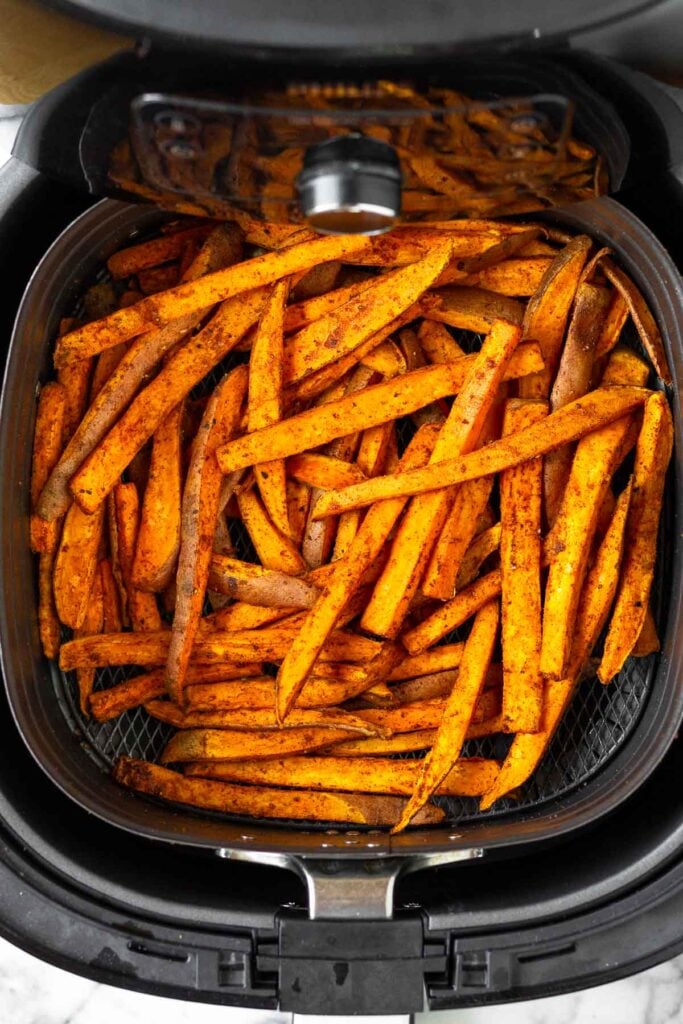 Partially cooked sweet potato fries in an air fryer.