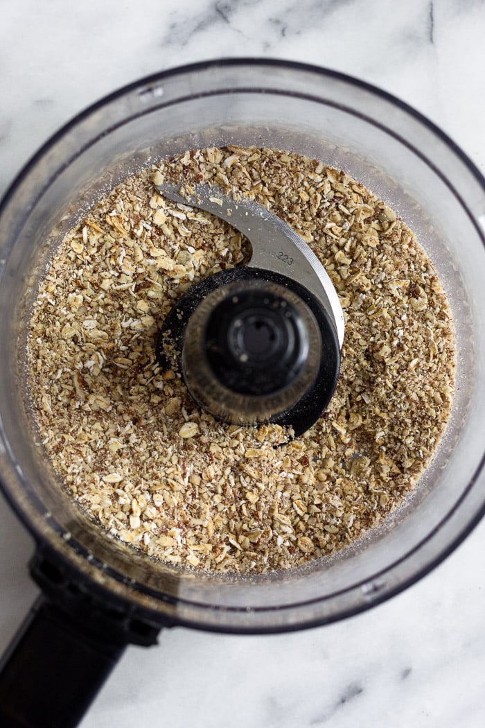 Food processor with sound up pecans and oats in it.