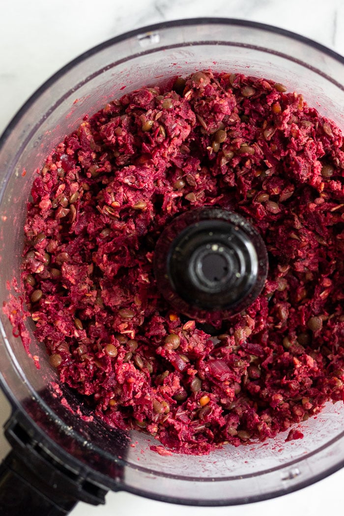 Food processor with beet lentil burger mixture in it.