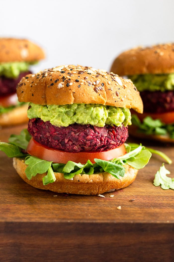 Wooden board with 3 beet burgers on it. One is in the front with 2 others behind it on both sides.