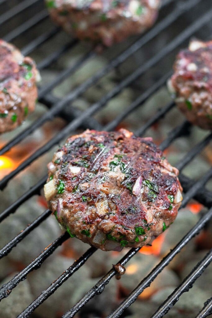 Burgers cooking on a charcoal grill.