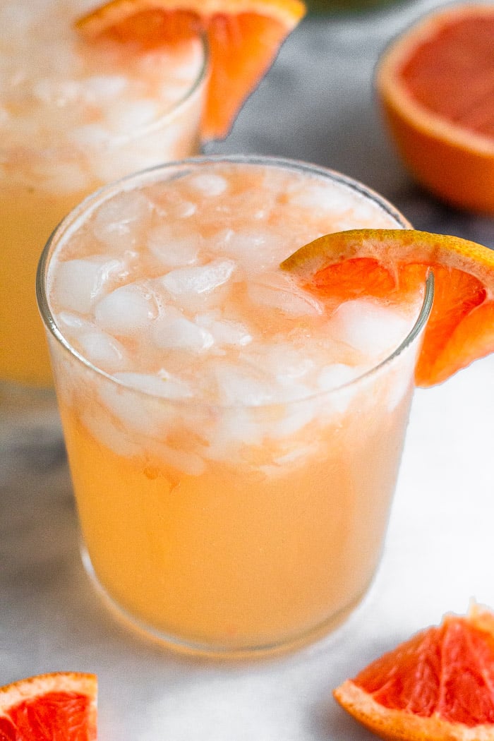 Close up of an overhead shot of a grapefruit vodka cocktail and garnished with a grapefruit wedge.