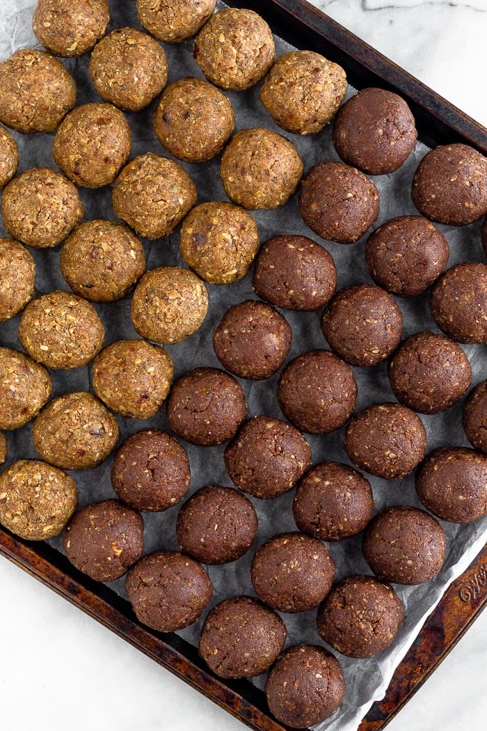 Cookie sheet lined with parchment paper with two kinds of Seed cycling date balls