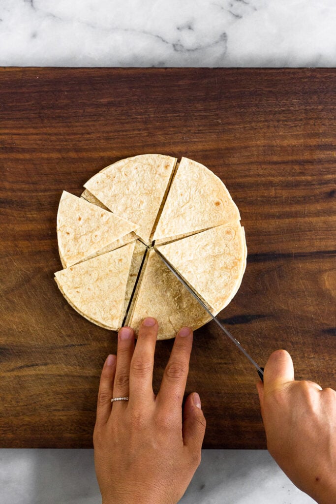 Overhead shot of corn tortillas being cup into triangles.