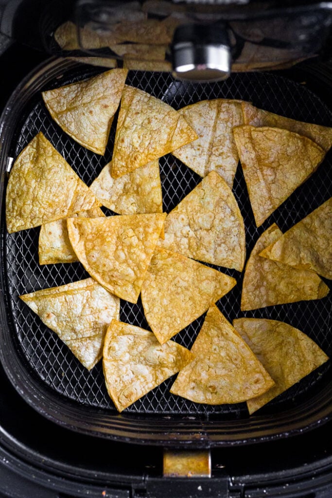 Homemade corn tortilla chips in an air fryer basket.