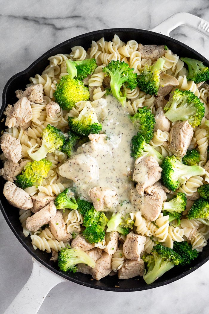 Overhead shot of a pan filled with chicken broccoli pasta with ranch dressing poured on top.