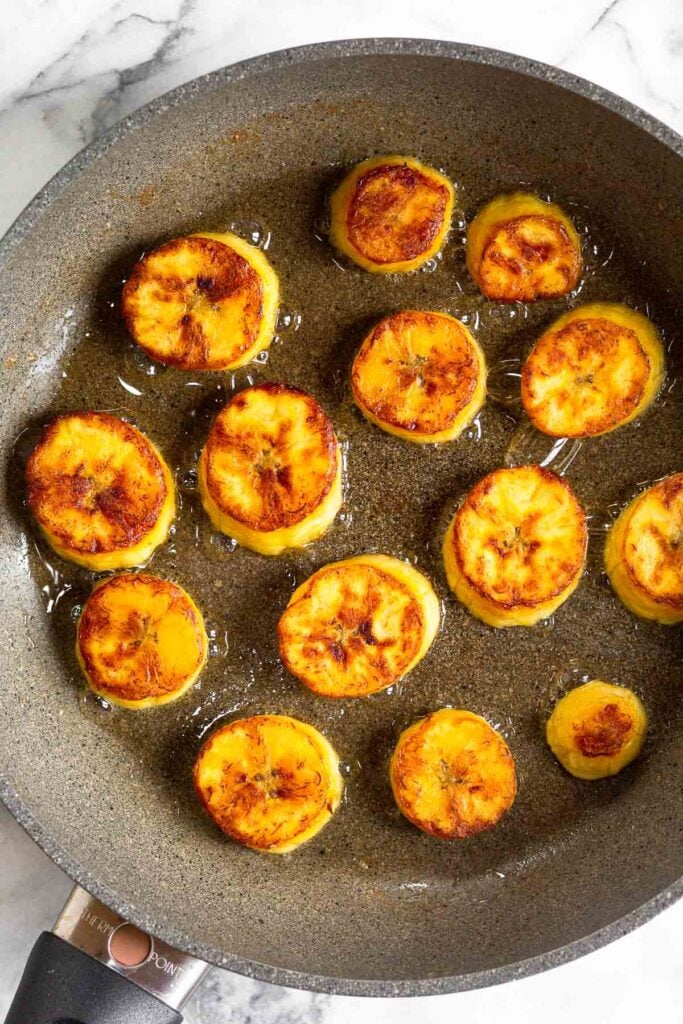 Sweet plantains frying in a skillet.