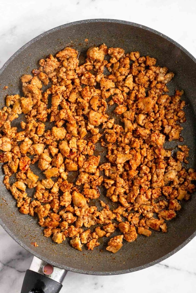 Large skillet filled with cooked ground sausage.