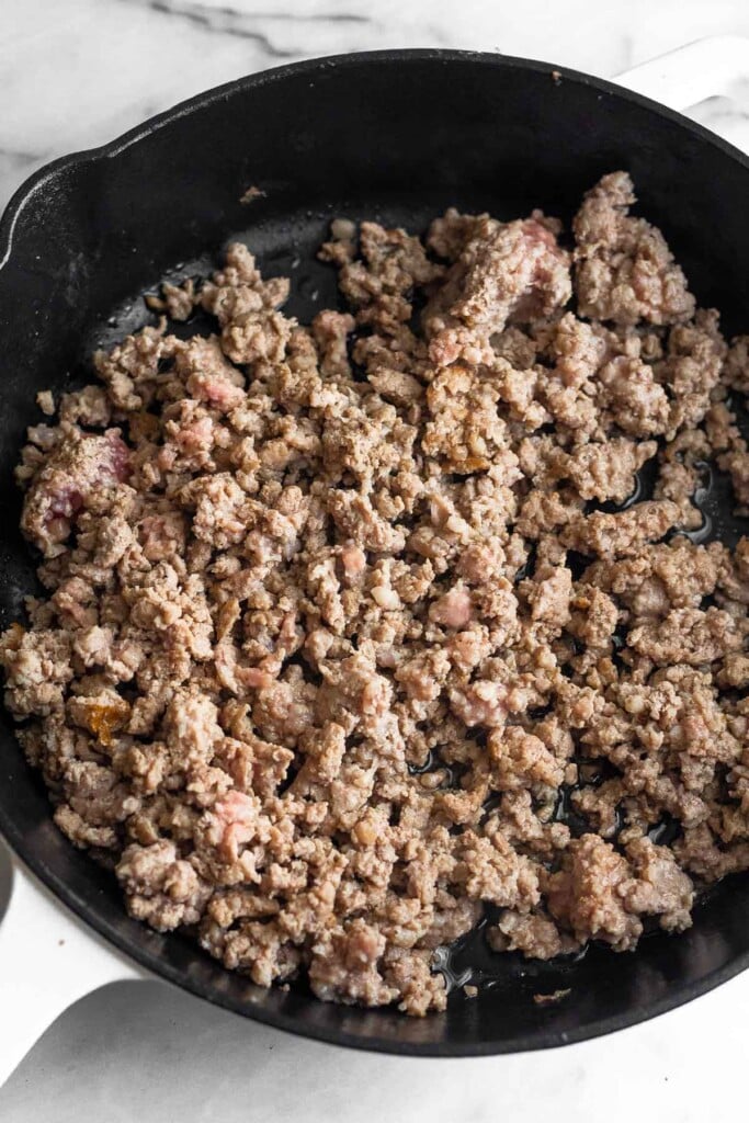 Large cast iron skilled filled with cooked ground sausage.