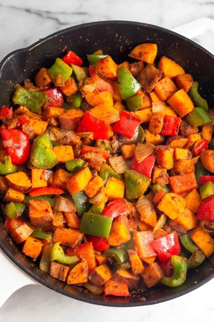 Large cast iron skilled filled with sautéed diced sweet potatoes, peppers, and onions.