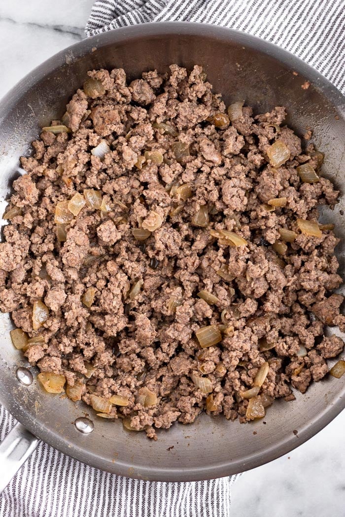 A pan filled with cooked ground beef and onions.