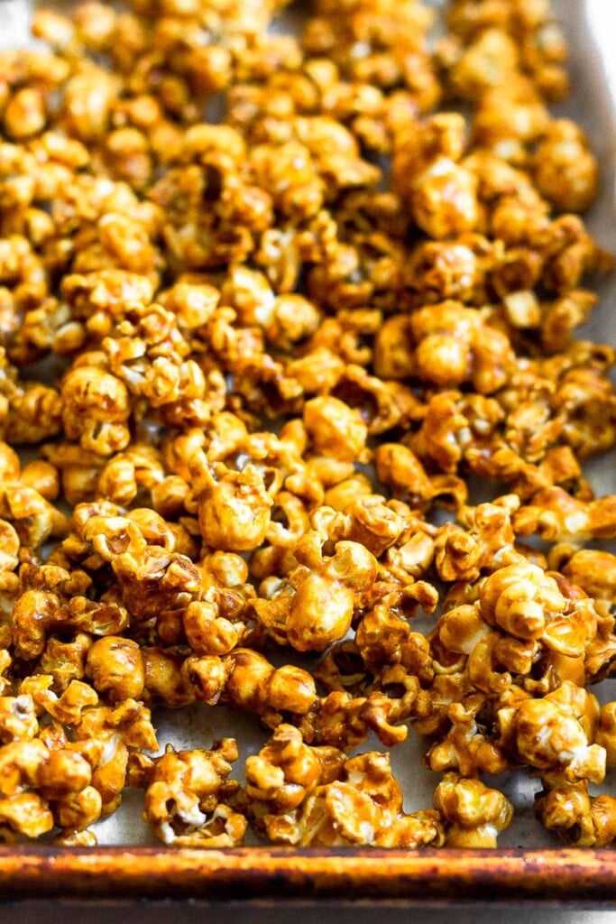 Large baking sheet filled with homemade caramel popcorn without corn syrup.
