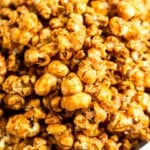 A close up shot of homemade caramel popcorn in a white bowl.