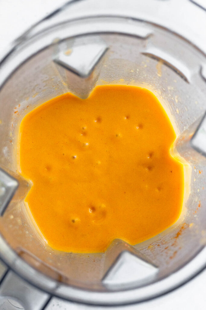 Blender filled with a creamy orange broth.