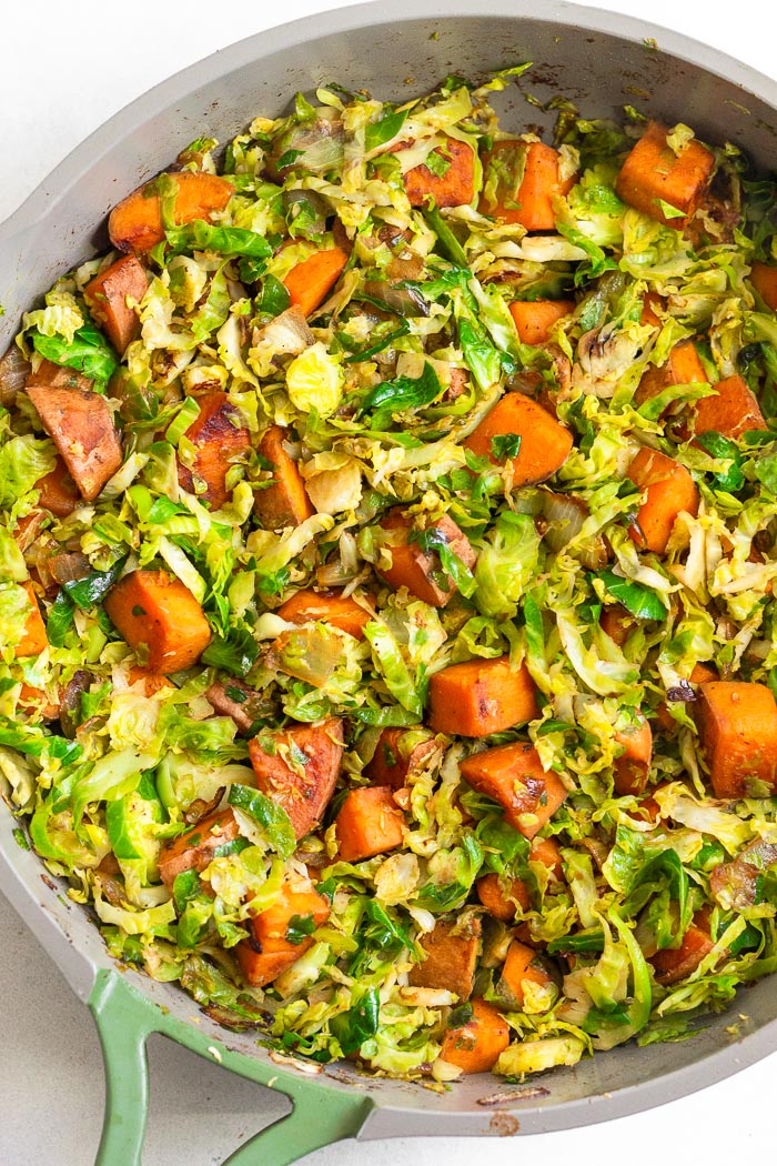 Skillet filled with cooked sweet potatoes and shredded Brussel sprouts.