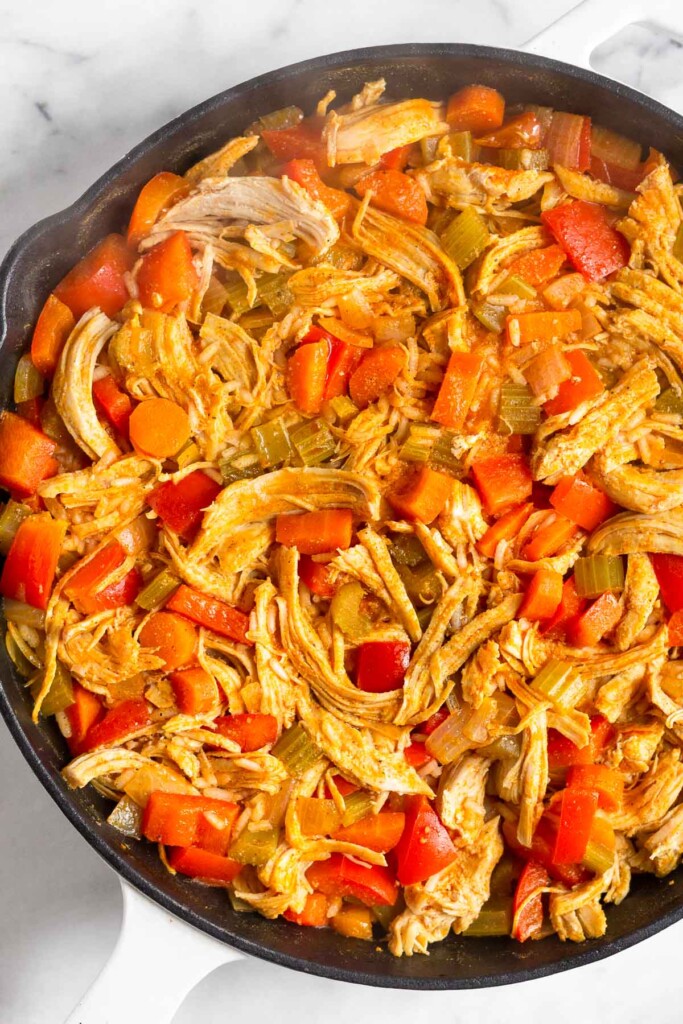Chicken and rice casserole with veggies in a large cast iron skillet.