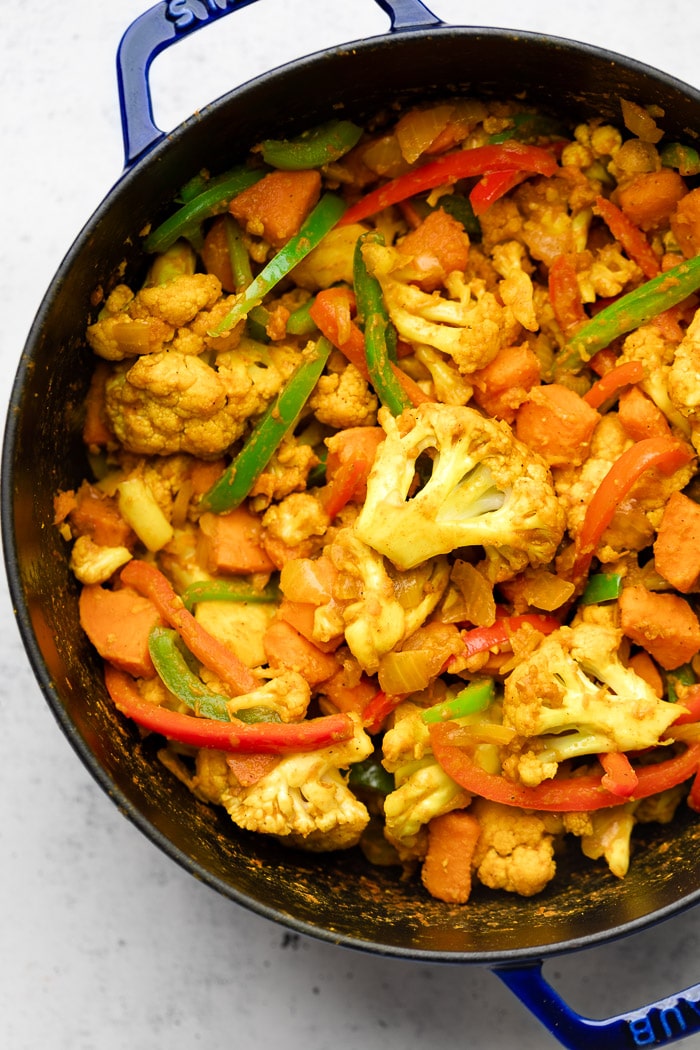 Large dutch oven filled with a bunch of veggie flavored with curry spices.