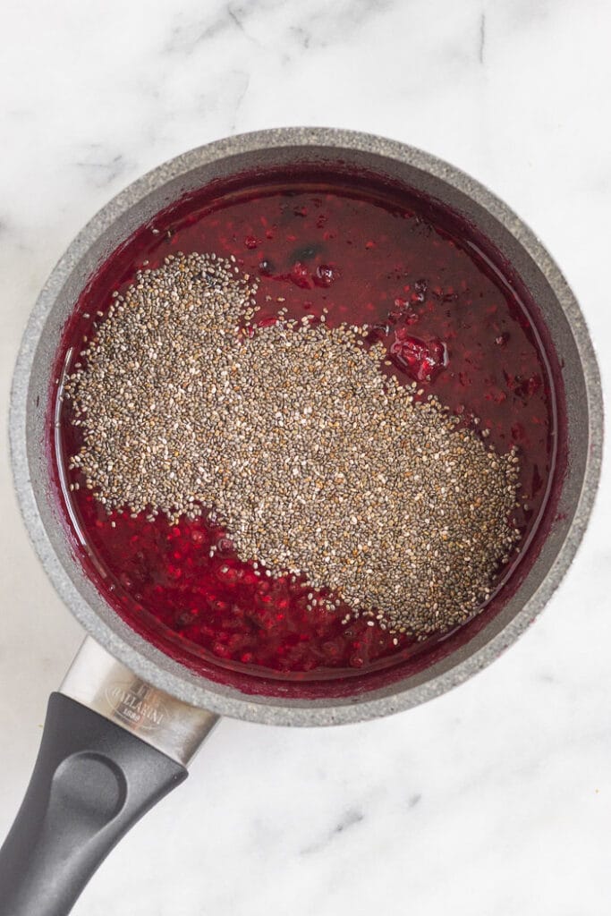 A saucepan filled with cooked down berries with chia seeds sprinkled on top.