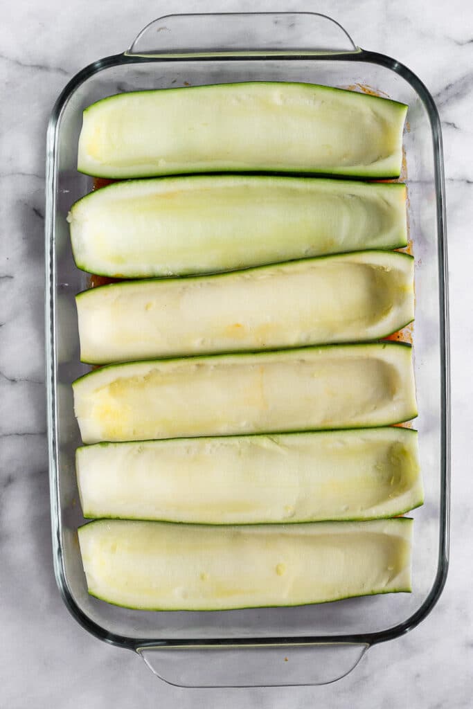 Overhead shot of zucchini boats in glass baking dish.