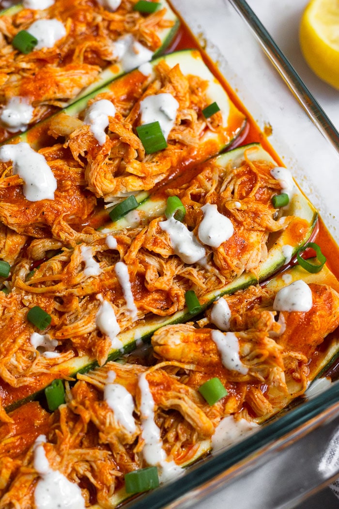 Healthy chicken zucchini boats topped with blue cheese dressing and green onions.