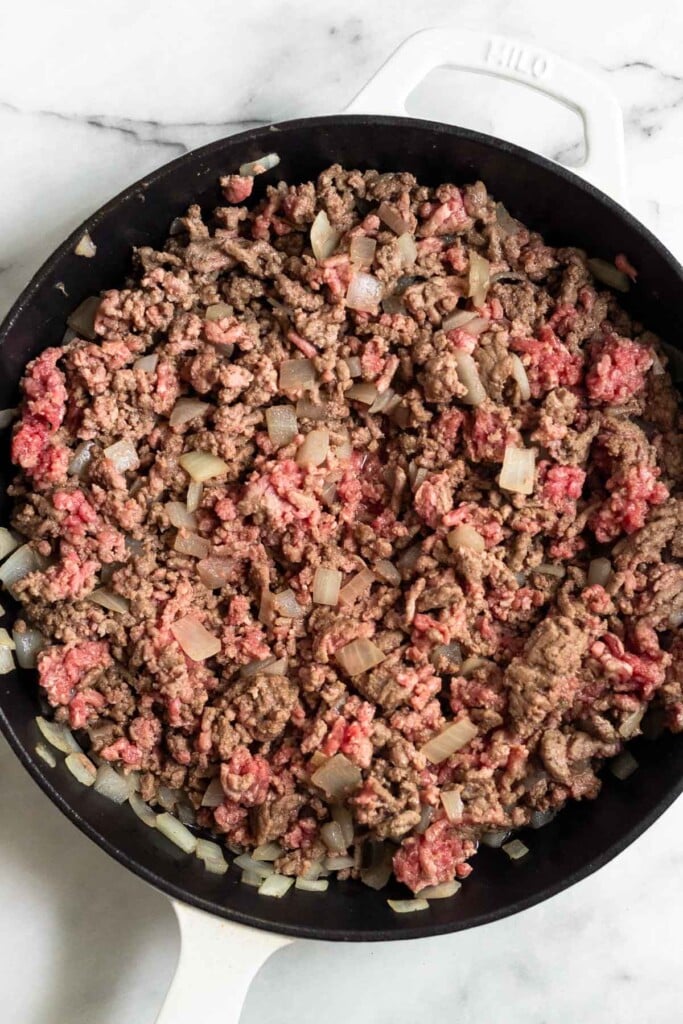 Pan filled with sautéed ground beef and diced onions.