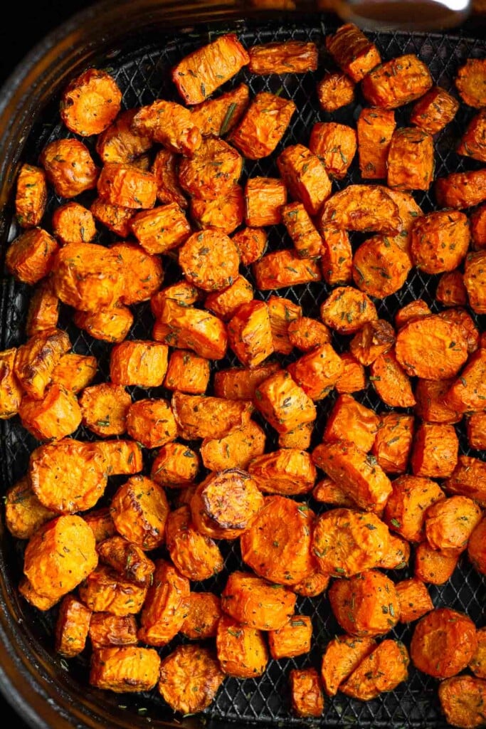 Overhead shot of roasted carrots in an air fryer basket.