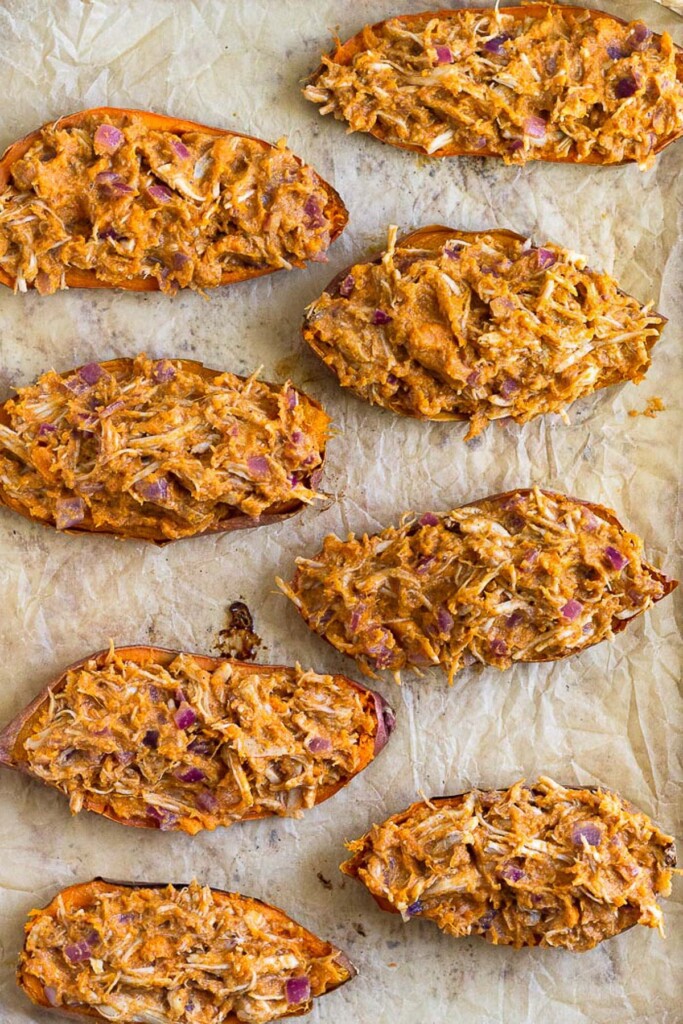 Sweet potato skins stuffed with barbecue chicken on a baking sheet before they are baked.