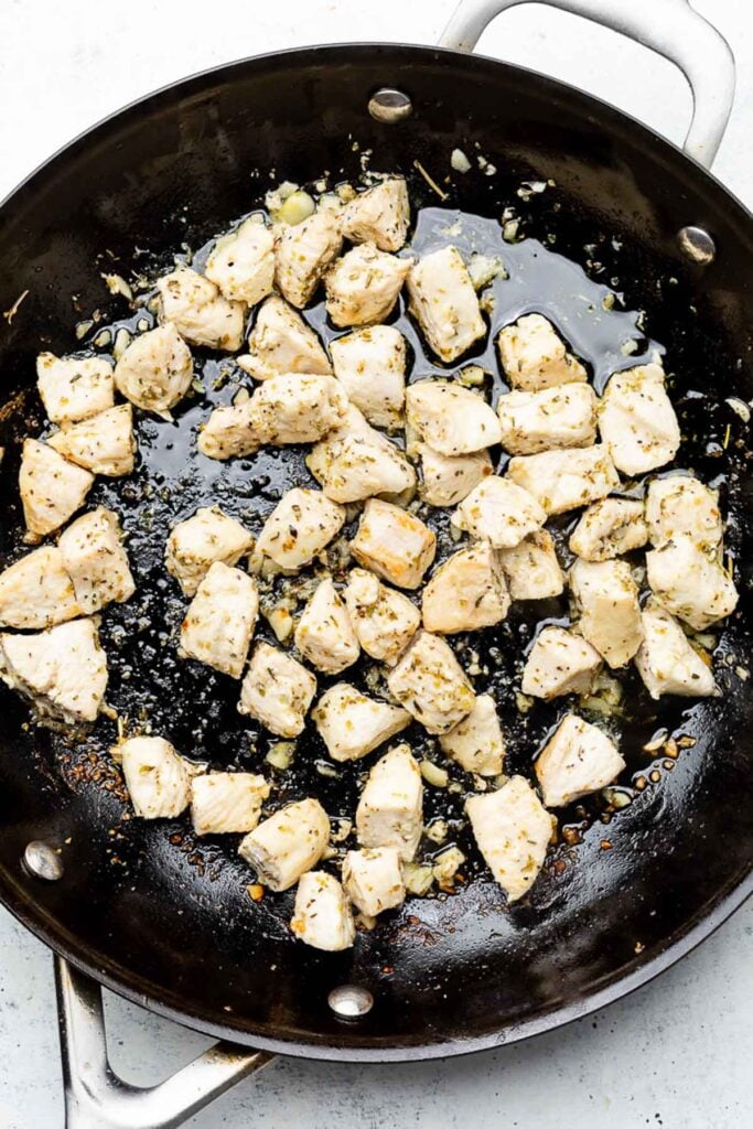 Pieces of diced sautéed chicken in a skillet.