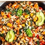 Ground turkey and sweet potato skillet with melted cheese in a large cast iron. It is topped with sliced avocado, jalapeño, and cilantro.