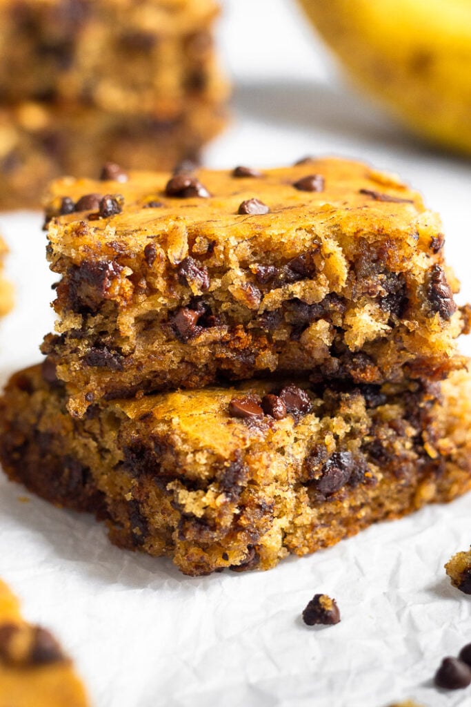 Two easy banana bread bars stocked on top of each other. Around them are more bars and chocolate chips.