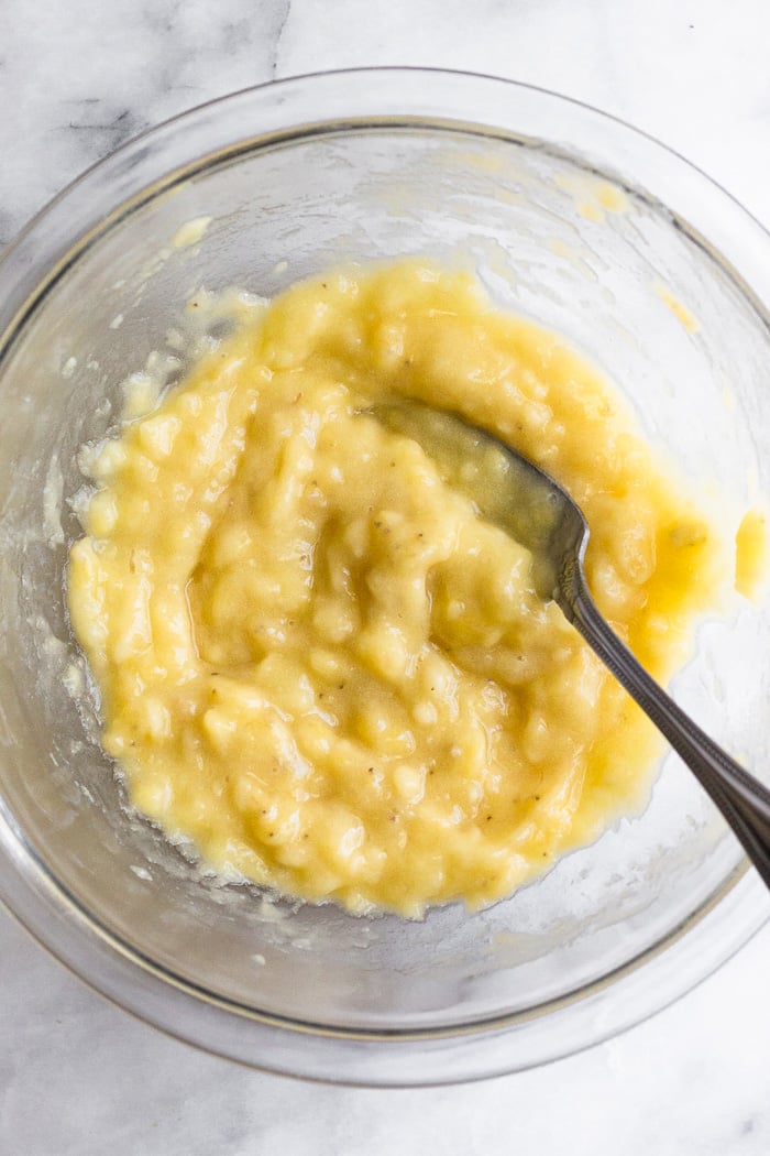 Bowl of mashed bananas with a fork in it.