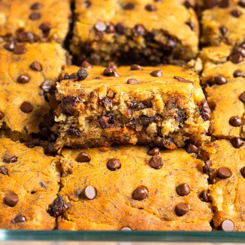 A pan of banana bread bars with one of the bars higher than the others so you can see the inside of it.