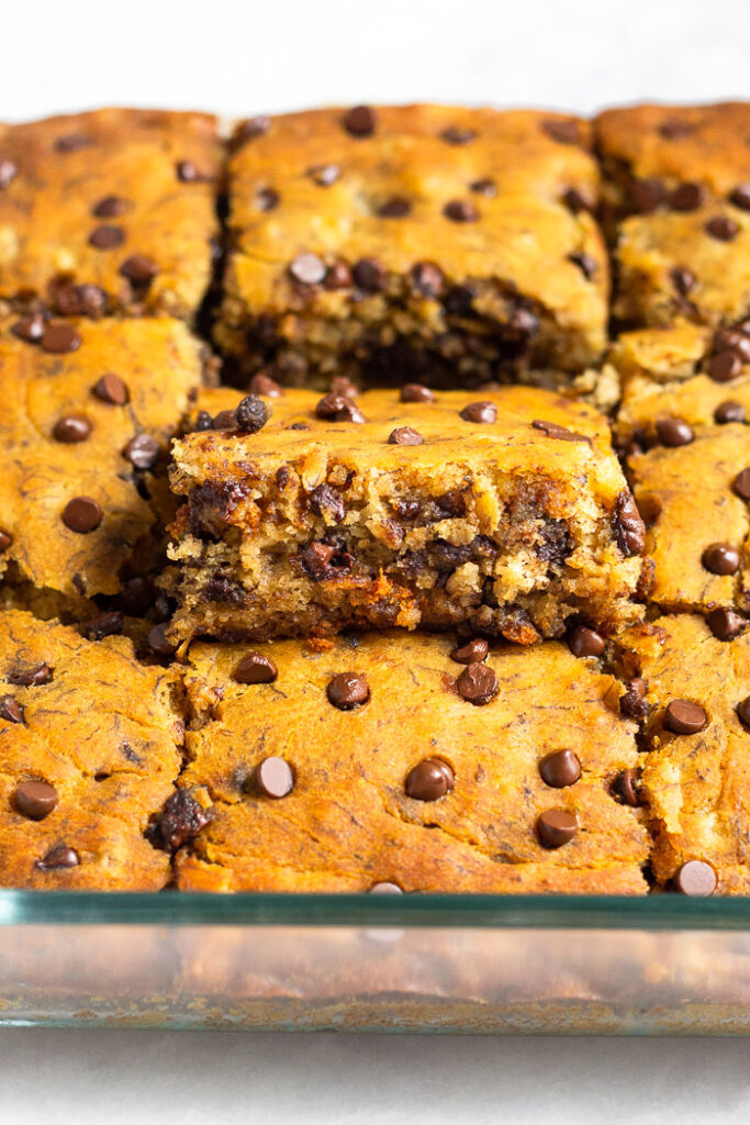 A pan of banana bread bars with one of the bars higher than the others so you can see the inside of it.
