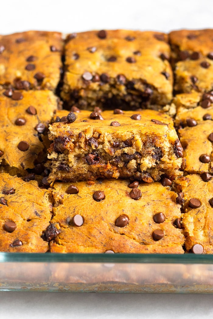 A pan of banana bread bars with one of the bars higher than the others so you can see the inside of it.
