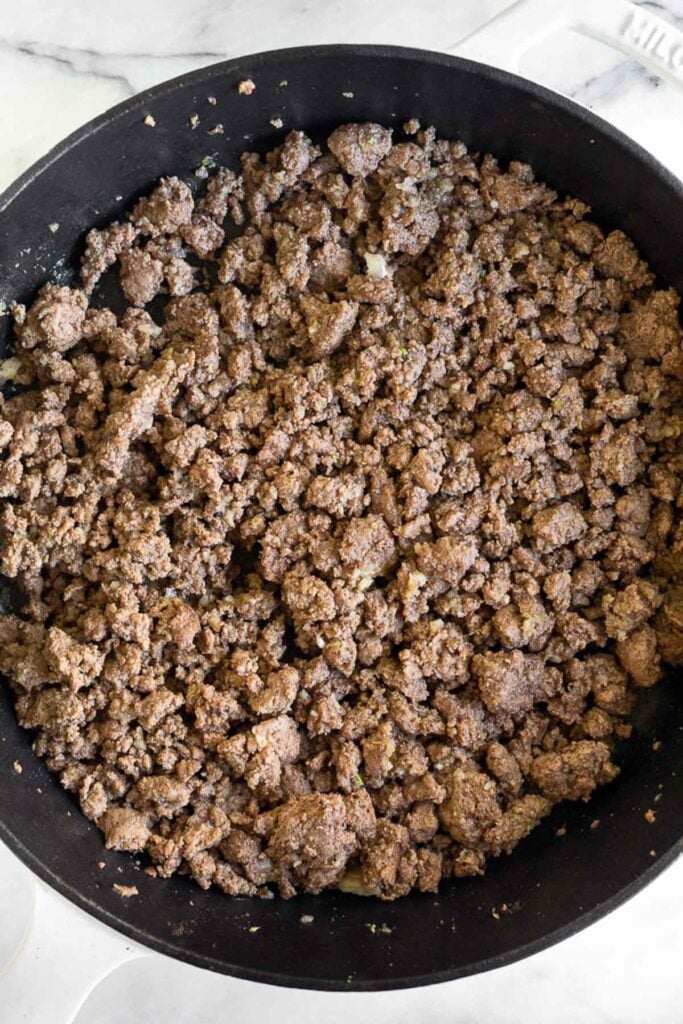 Cast iron skillet filled with sautéed ground beef.