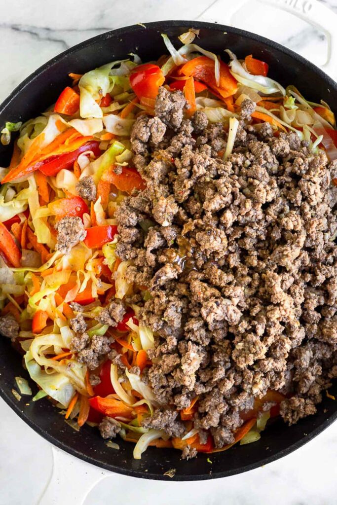 Large cast iron will sautéed veggies and ground beef on top of them.