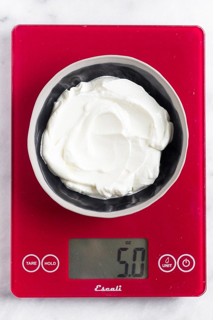 A bowl filled with yogurt on a food scale.