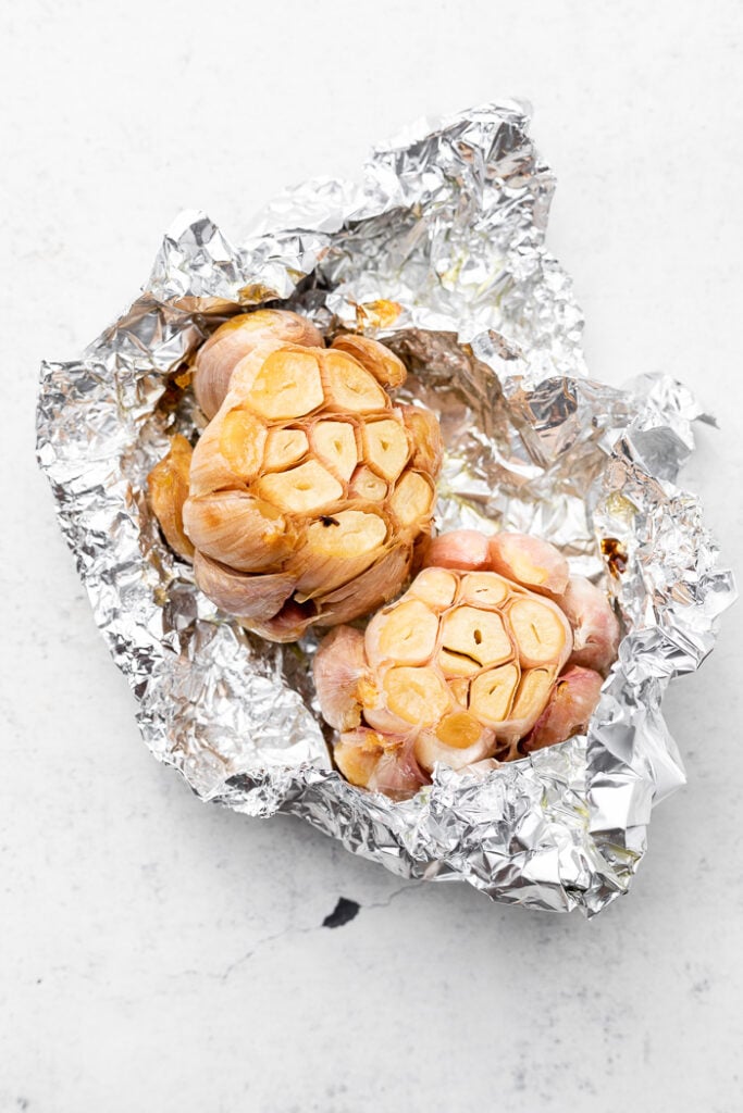 Two heads of roasted garlic in tinfoil.