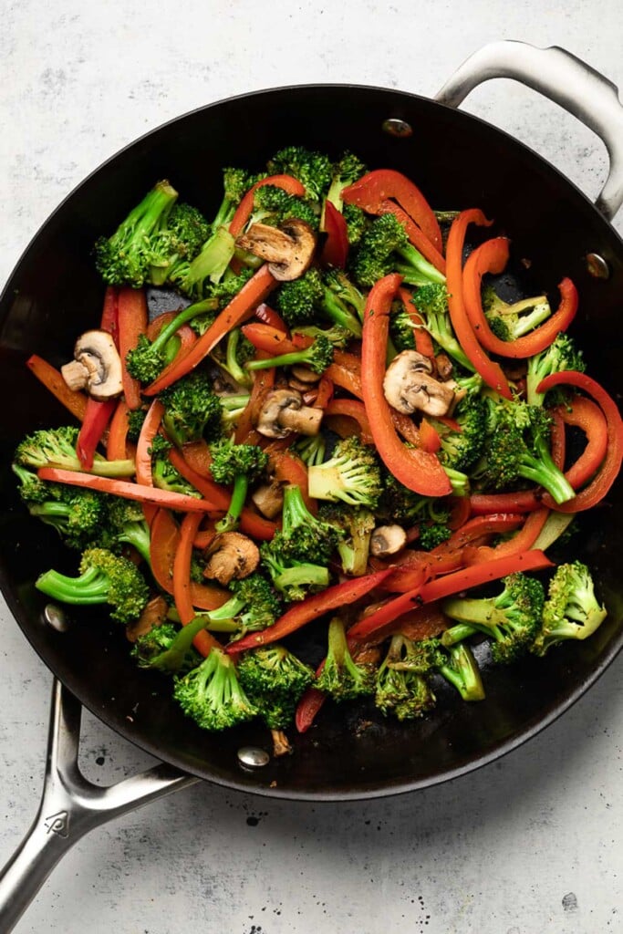 Large skillet with sautéed broccoli, peppers, and mushrooms.