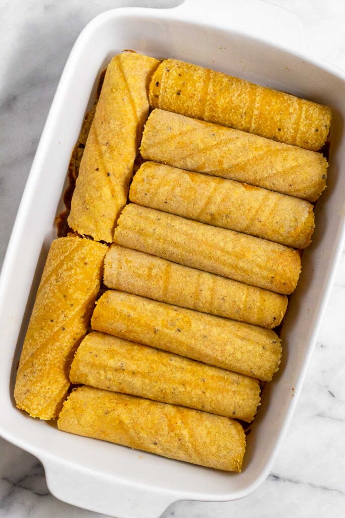 Casserole dish filled with rolled enchiladas before any sauce is put on top.