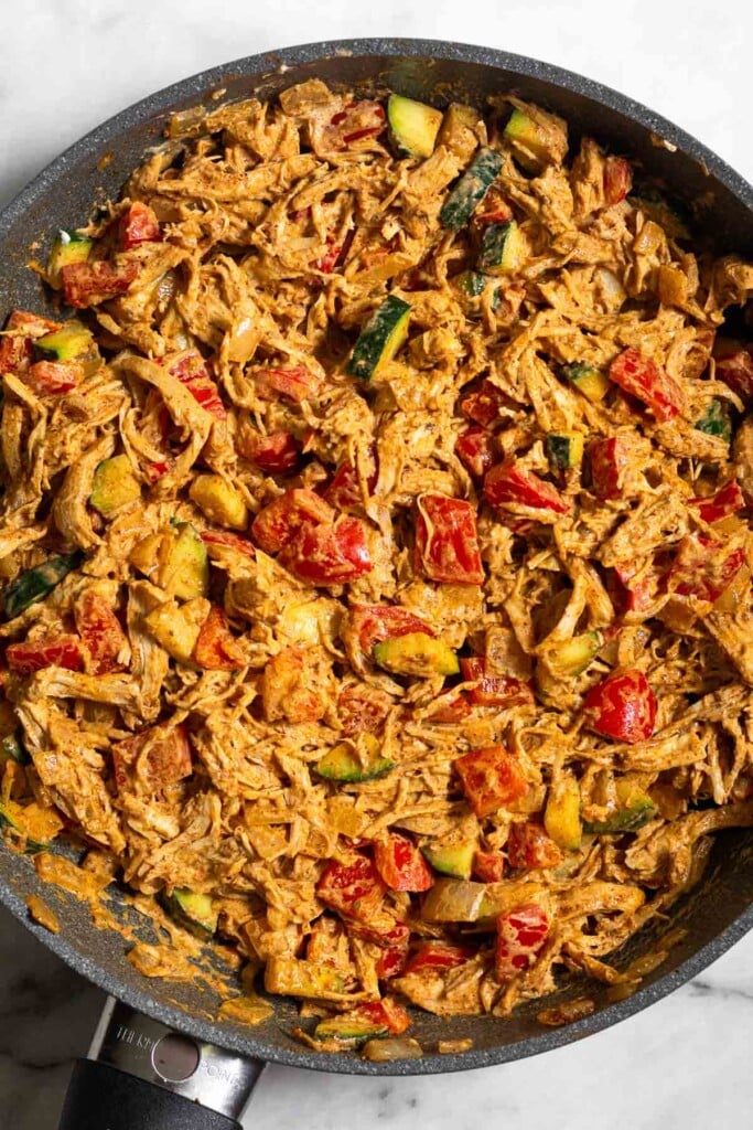 Skillet filled with a mix of chicken and veggies tossed in a creamy sauce.