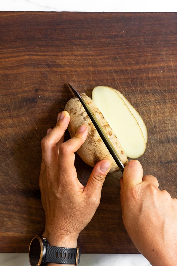 Overhead shot of someone cutting a potato lengthwise.